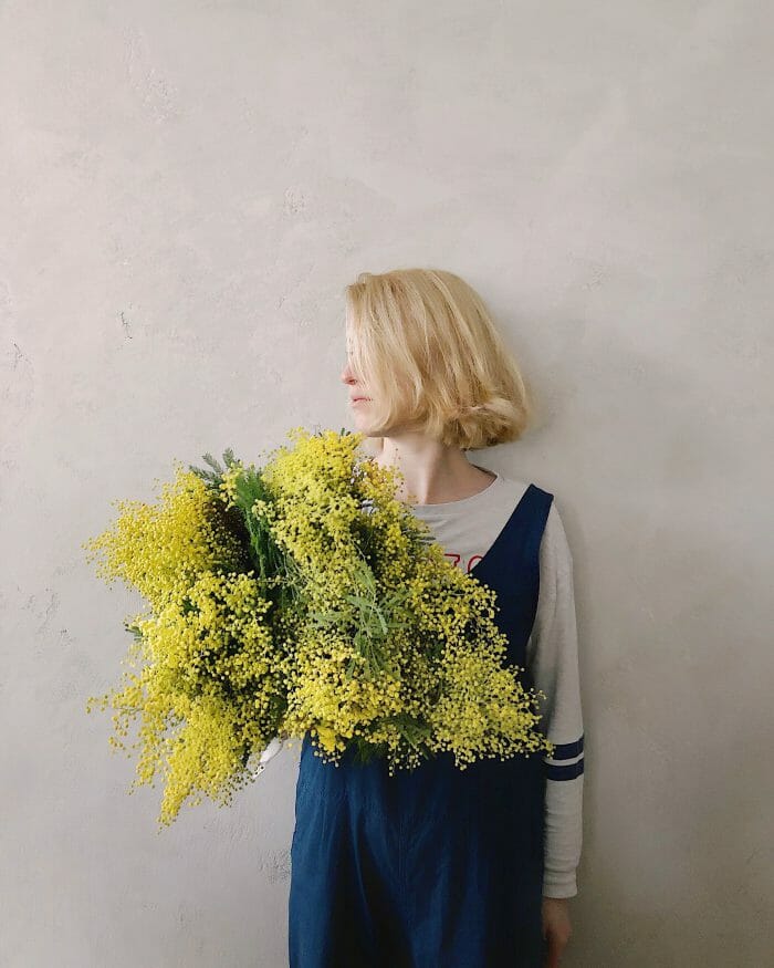 feminine blonde person holding a bouquet of flowers