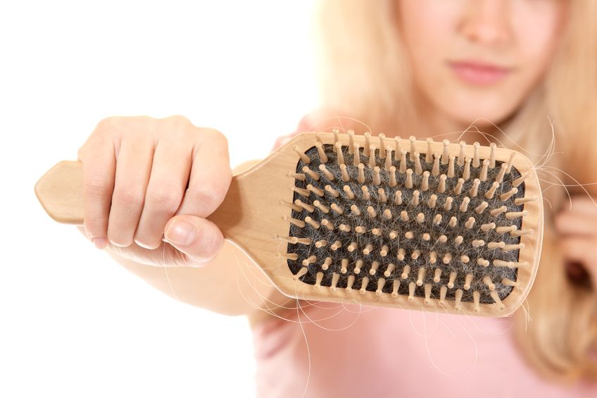 women with hair problem holding loss hair comb in hand